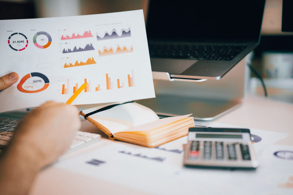 A business professional reviews colorful marketing analytics charts and graphs alongside a calculator and notebook, illustrating what percentage of revenue should a small business spend on marketing